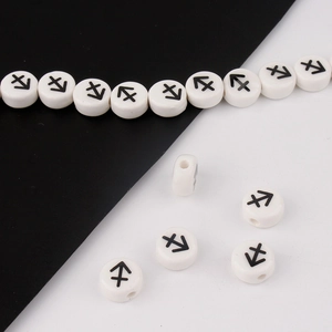 Macro detail of white ceramic beads with black Sagittarius zodiac symbols for DIY bracelets