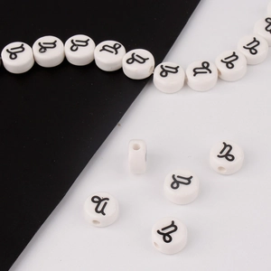 Detailed macro view of white ceramic Capricorn zodiac beads with black printed symbols