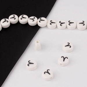 Macro detail of white ceramic bead with Aries zodiac symbol and precise drill hole