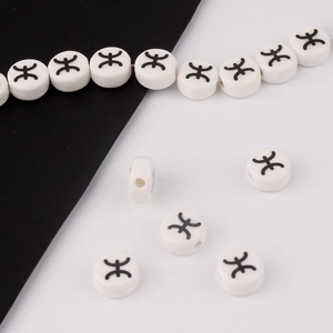 Detailed view of white ceramic beads with black ethnic symbols for DIY jewelry making