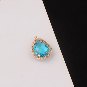 Detalle de colgante de gota en cristal azul cielo con base de encaje dorado labrado