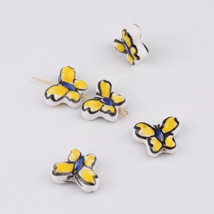 Detailed view of hand-painted yellow ceramic butterfly beads for DIY jewelry making