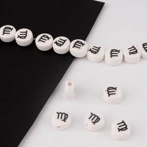 Close-up of white round ceramic beads with black Virgo zodiac sign for DIY bracelets