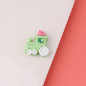Macro view of cartoon green train resin accessory with pink bow for DIY crafts