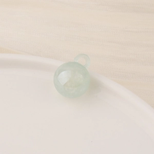 Macro shot of a translucent light green ball pendant with integrated loop on ceramic