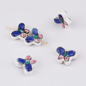 Detailed view of hand-painted butterfly ceramic beads with gold pin for DIY jewelry