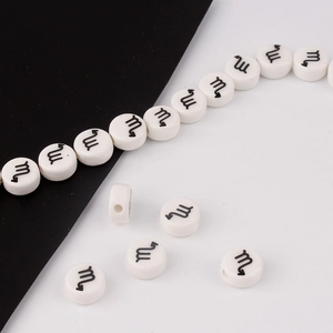 Macro view of white ceramic zodiac beads with black Scorpio symbols for DIY jewelry