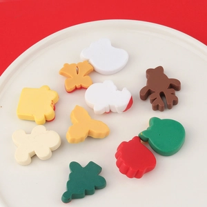 DIY Christmas resin charms with reindeer and Santa shapes on a white ceramic plate