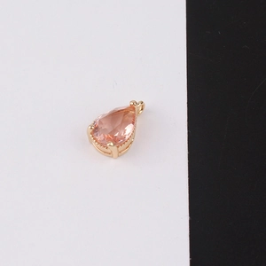 Detailed view of teardrop pink crystal pendant with gold plating on black and white background
