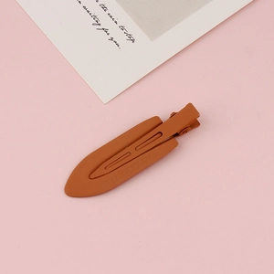 Close-up of light brown matte metal duckbill hair clip with embossed brand lettering