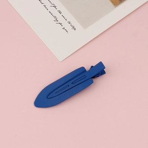 Detailed macro view of dark blue matte metal hair clip on a pink paper background