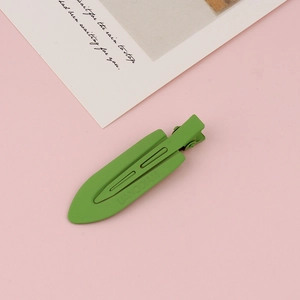 Close-up of grass green matte duckbill hair clip with textured metal finish and UANODIAM logo