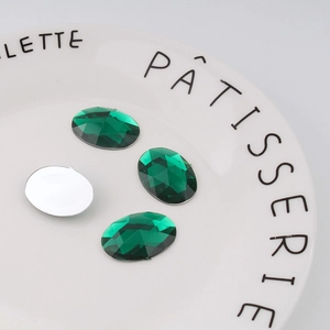Macro detail of emerald oval acrylic rhinestones showing faceted top and silver flat back