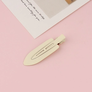 Close-up of cream matte seamless hair clip with anti-slip grooves on pink background