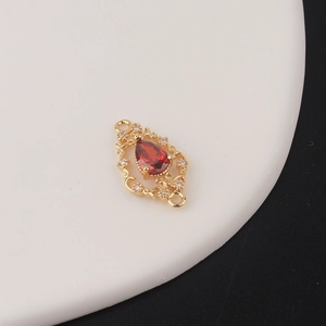 Detailed close-up of golden teardrop pendant with red zircon stone and filigree metal work