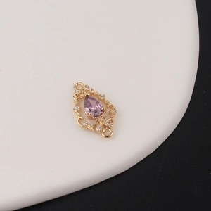 Detail of gold hollow teardrop pendant with purple zircon inlay for DIY jewelry making