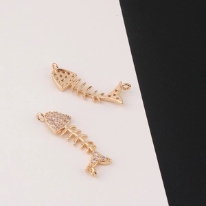 Detail view of gold-plated fishbone pendants with white zircon inlays and dual loops
