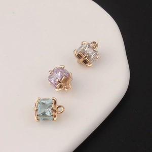 Macro shot of square zirconia charms with gold plating and hanging loops for DIY jewelry