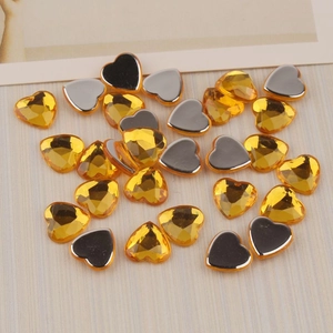 Detailed macro view of 12mm amber heart-shaped flatback acrylic rhinestones for DIY crafts