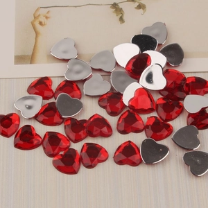 Macro detail of 12mm red heart flatback acrylic rhinestones with faceted surface