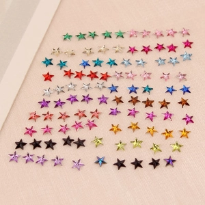 Vue macro de strass pour ongles en forme d'étoile de 3mm sur un fond de tissu texturé