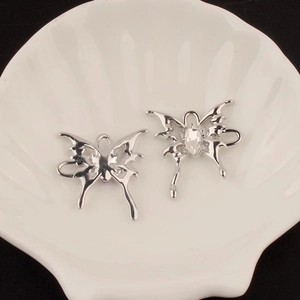 Detail view of silver hollow butterfly charms with crystal inlay on a white shell plate