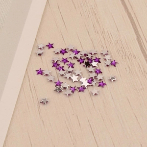 Vue macro de breloques d'ongles en forme d'étoile violette de 3mm sur bois clair