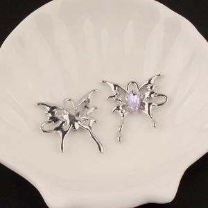 Detailed macro view of silver Y2K butterfly charms with purple crystals and metal hooks