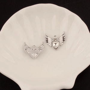 Detail view of silver angel wing charms with heart-shaped zircon for DIY jewelry making