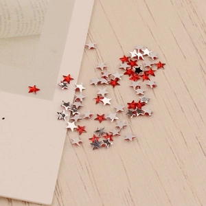 Détail macro de paillettes d'ongles en forme d'étoile rouge et argent de 3mm sur bois