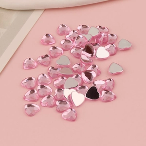 Vista macro di strass in acrilico rosa a forma di cuore con retro piatto per decorazioni fai-da-te