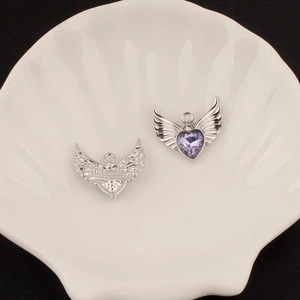 Y2K silver angel wing heart charm with purple gemstone in shell tray macro detail