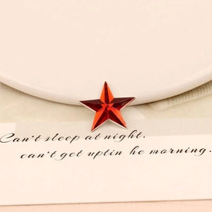 Macro view of red star-shaped acrylic rhinestone with faceted cut and silver trim