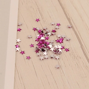 Détails de paillettes d'ongles en forme d'étoile de 3mm sur un fond de bois