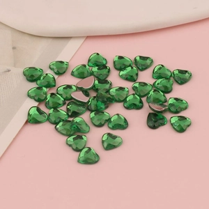 Dettaglio macro di strass acrilici a forma di cuore verde smeraldo con base piatta argento