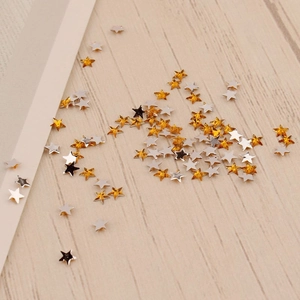Vue macro de paillettes étoiles de 3mm or et argent pour nail art sur fond de bois