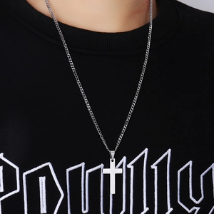 Polished silver stainless steel cross pendant necklace worn over a black hoodie