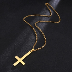 Detailed macro view of the polished golden inverted cross pendant on a dark background