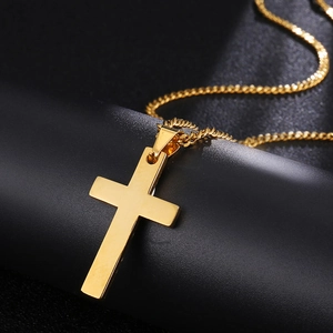 Macro shot of polished gold-finished stainless steel cross pendant on black stand
