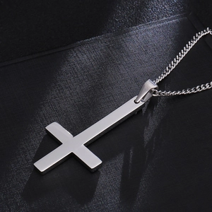Macro detail of polished stainless steel St. Peter inverted cross pendant on curb chain