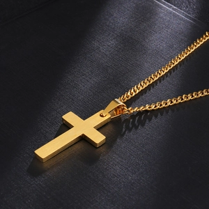 Macro shot of gold brushed stainless steel cross pendant on a sleek curb chain necklace