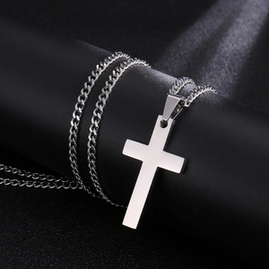 Detailed close-up of polished silver stainless steel cross pendant with cuban chain