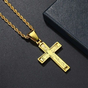 Detail of golden cross pendant with textured finish on a thick gold rope chain
