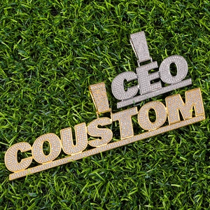 Hip-hop iced-out custom letter pendants in gold and silver finish on green grass