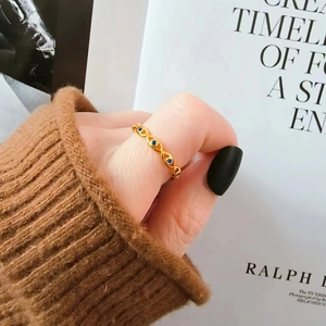 Eleganter goldener Ring mit blauem Teufelsauge und Zirkon-Steinen am Finger einer Frau