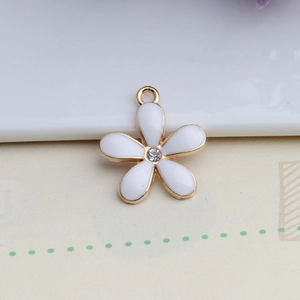 Detailed macro of golden alloy five-petal flower pendant with white enamel and center crystal