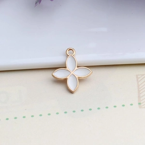 Detail of four-leaf flower charm with gold frame and white enamel for DIY jewelry