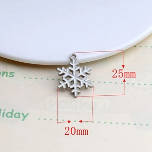 Detailed view of white enamel snowflake charm with silver edges measuring 25mm by 20mm