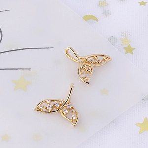 Macro shot of gold-plated mermaid tail charms with sparkling cubic zirconia inlay