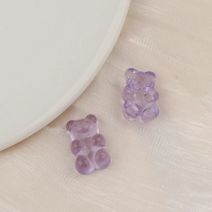 Close-up of translucent purple resin gummy bear charms on a textured background